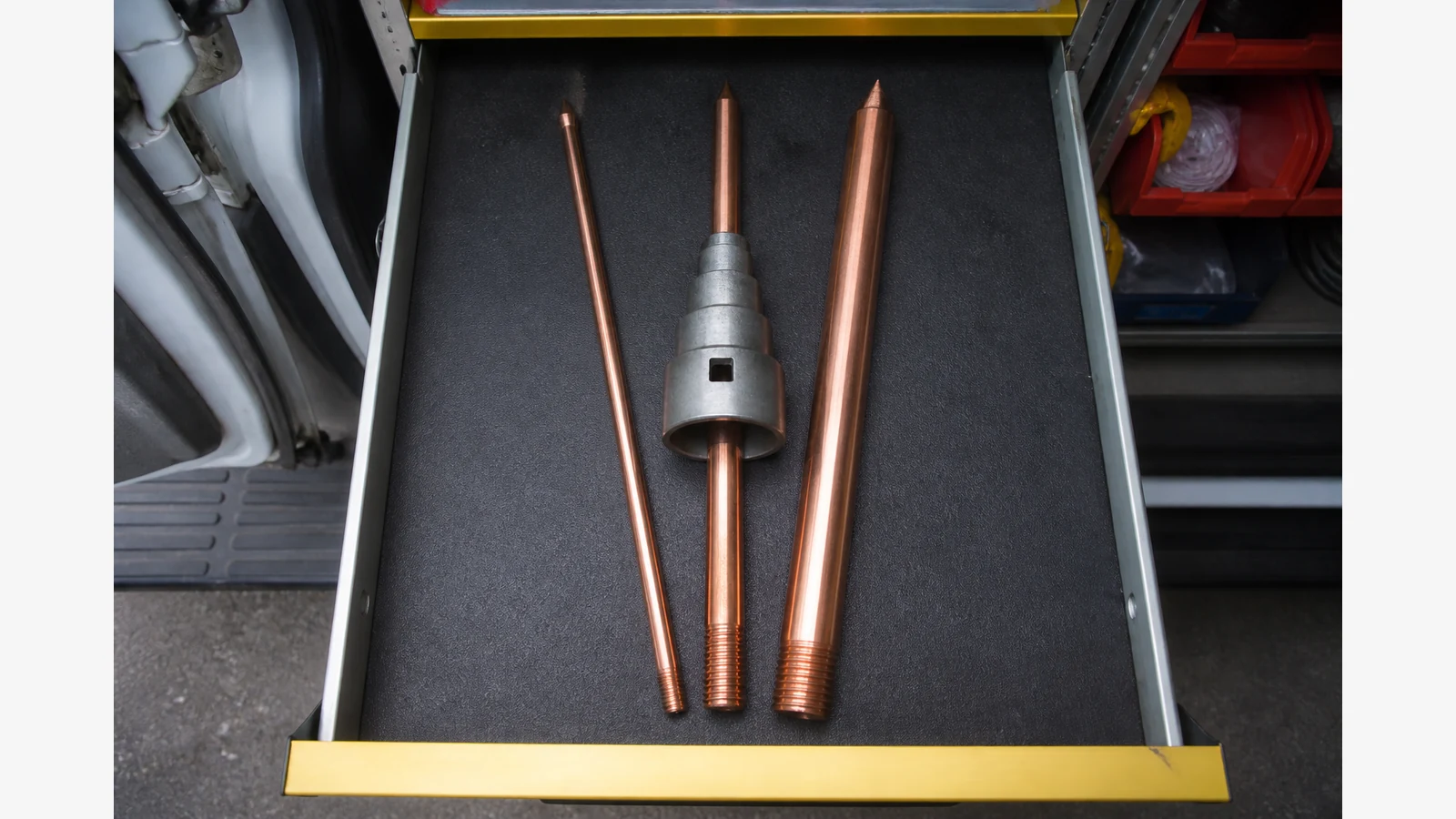 Mixed 1/2 5/8 and 3/4 copperbond earth rods beside a multi-size earth rod driver seat